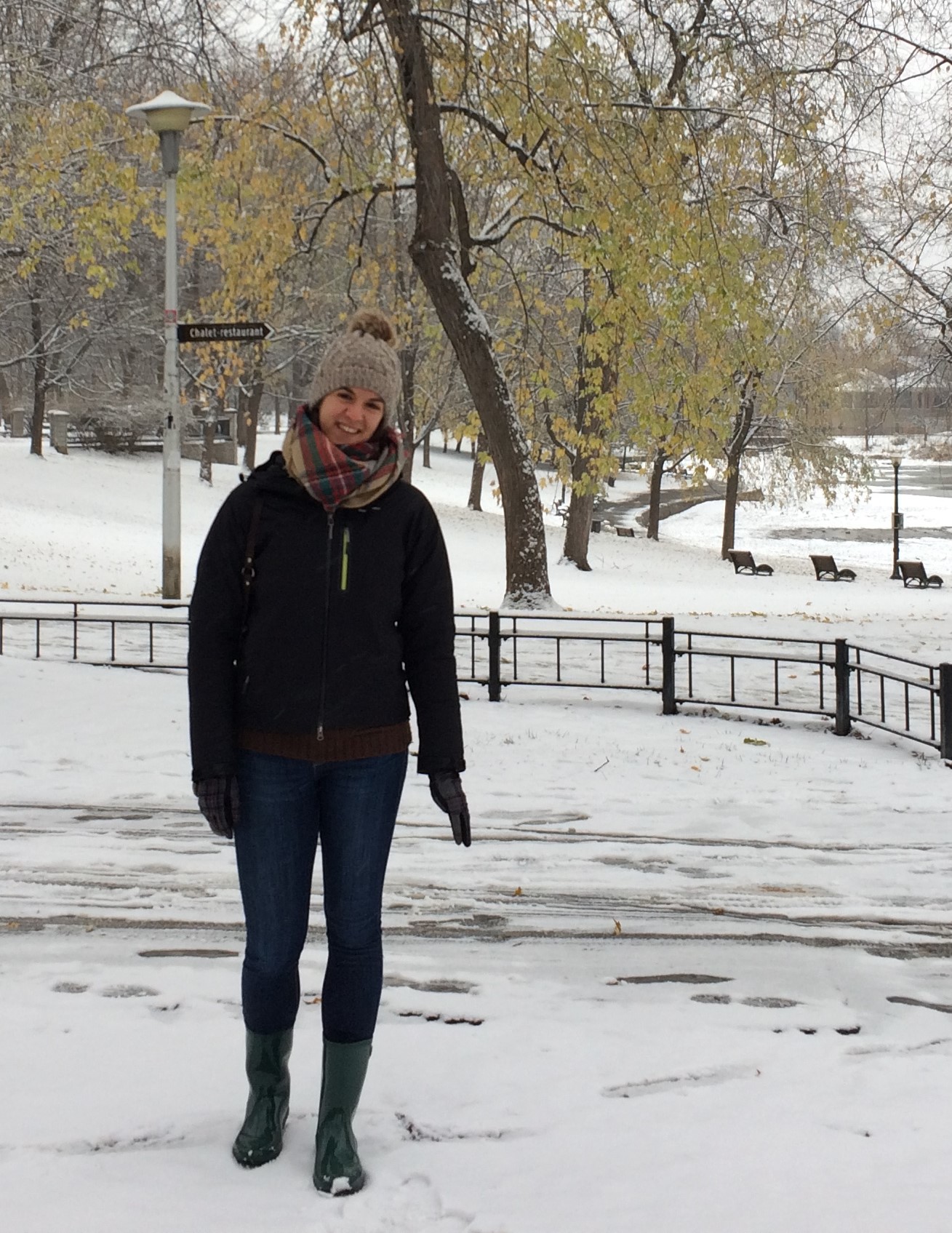 Ines all layered up with winter clothes posing in a park covered with snow