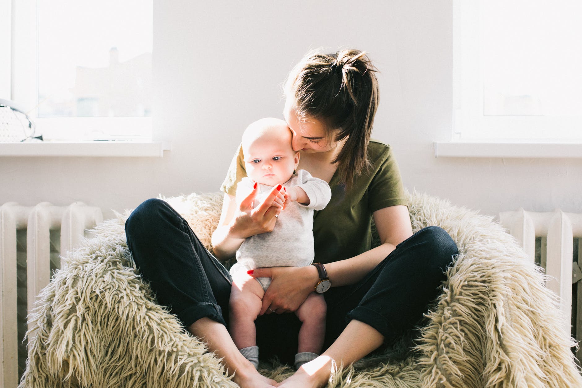 woman holding baby while sitting on fur bean bag