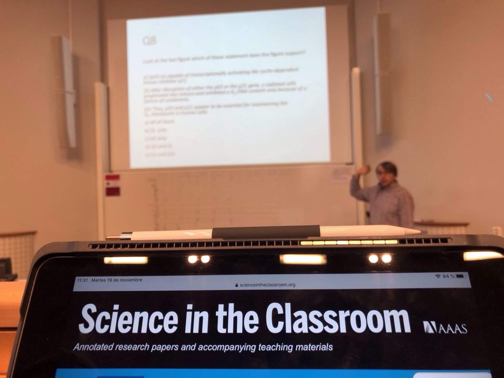 Science in The Classroom written on a tablet while a teacher points to a projected screen