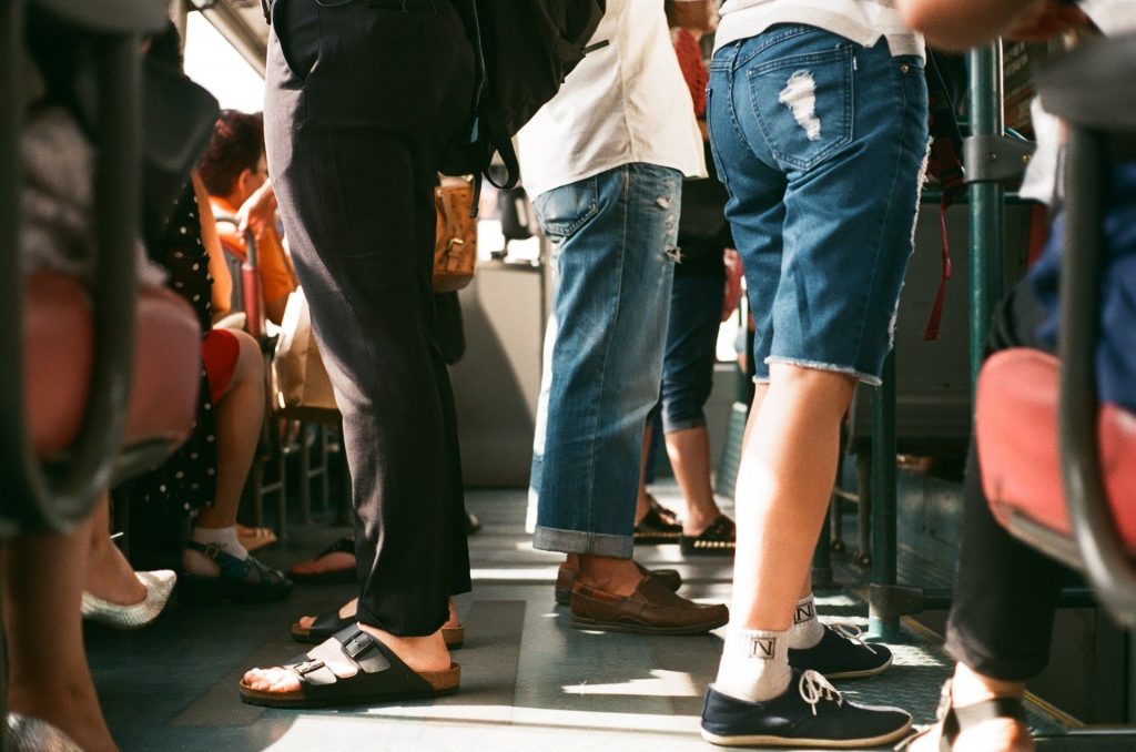 Several people standing, presumably in a bus. The image is taken from knee height, such that only their legs are visible.