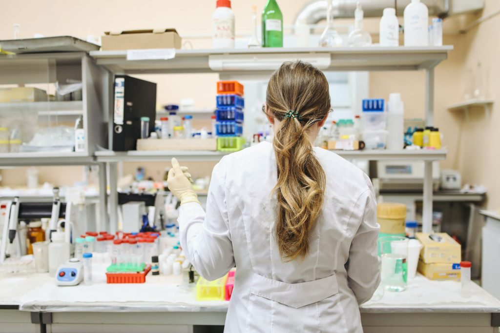 A person stands in front of a lab bench holding a pipette.