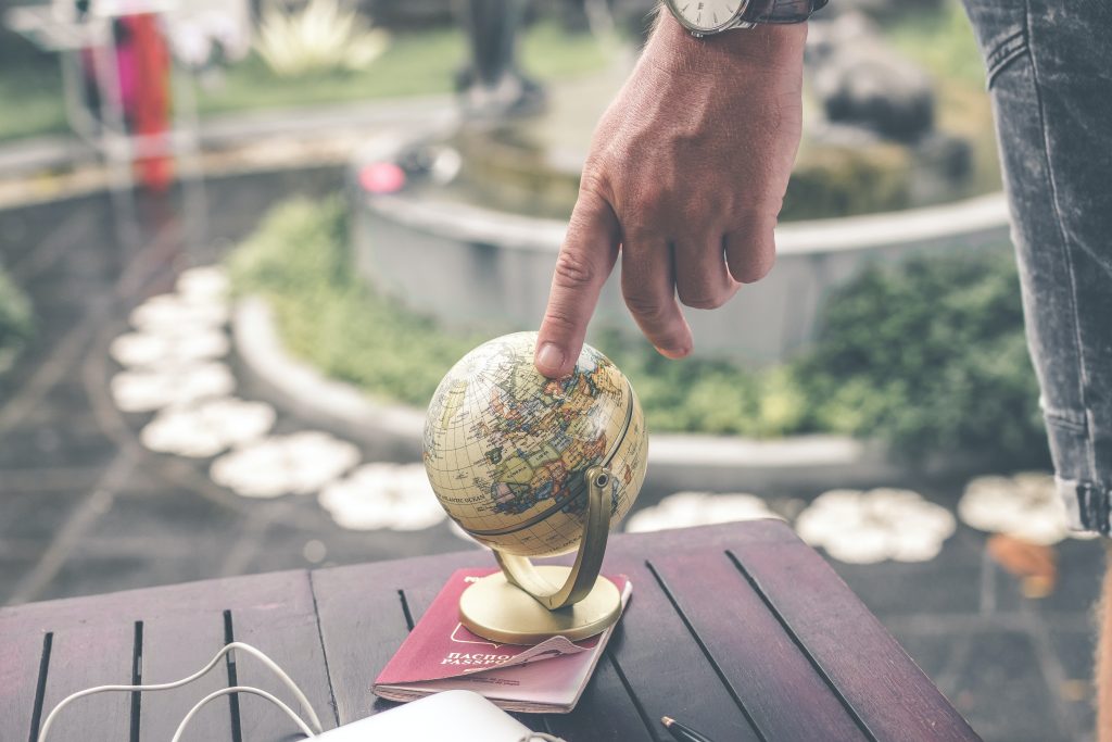 Someones finger grazes a globe that rests on top of a passport