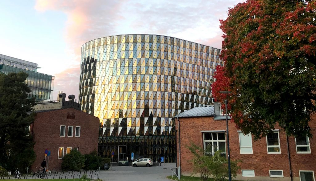 Aula Medica, a shiny building with a cloudy pink and blue sky as backdrop