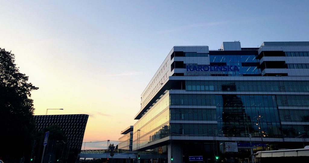 Karolinska University hospital on the right of Aula Medica. The sun set makes the sky glow yellow and blue
