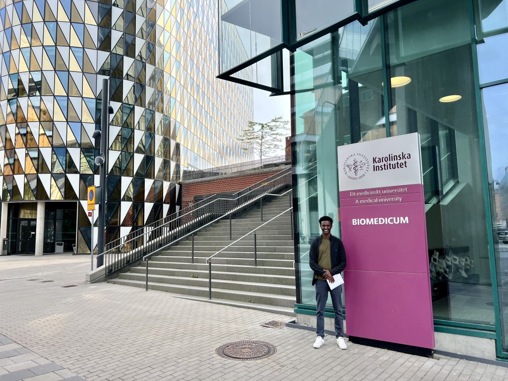 Yohannes in front of Campus Biomedicum with iconic Aula Medica building in the background.