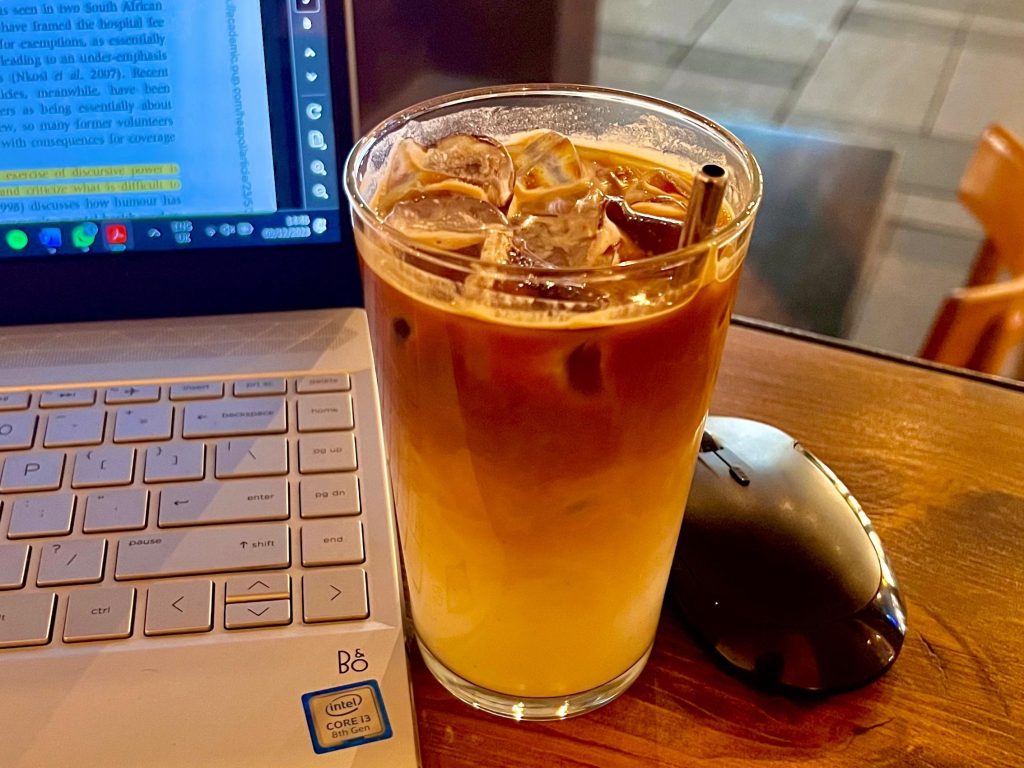 A picture of an iced coffee by the side of a laptop on a table