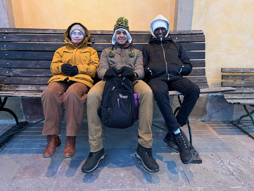 A picture of me and my two friends sitting on a bench outside the closed Botanical Garden. One part of the day trip to Uppsala