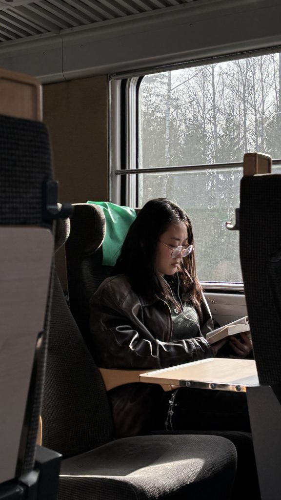 A girl reading a book on the train by the window seat
