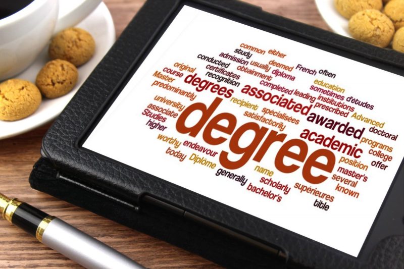 A tablet computer displaying the word ABC in a word cloud lying on a table top together with a pen, coffee and biscuits