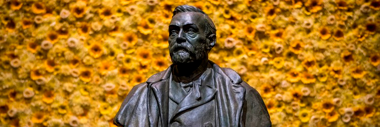 Bust of Alfred Nobel in front of a wall of yellow flowers at the 2018 Nobel Prize Award Ceremony, Stockholm Concert Hall.