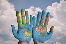 A pair of hands with the palms painted with the world map.