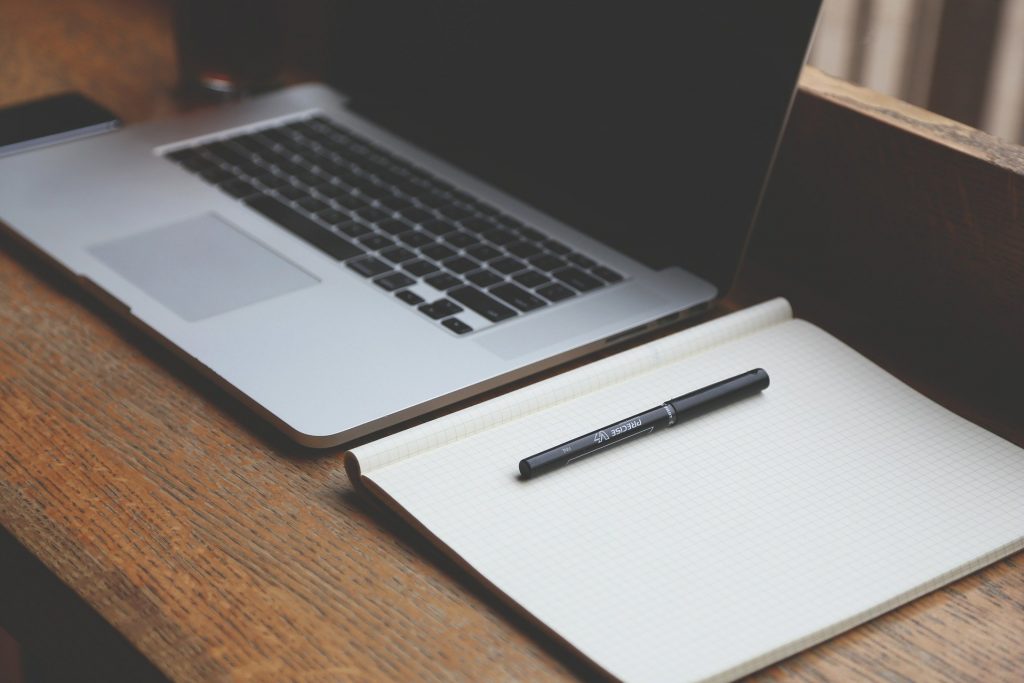 A laptop and a notebook side by side