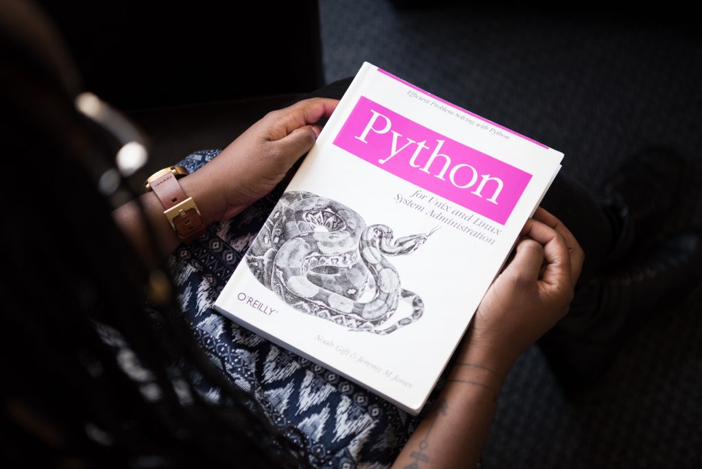 A person holding a book with the title Python and the cover image of a python snake on it