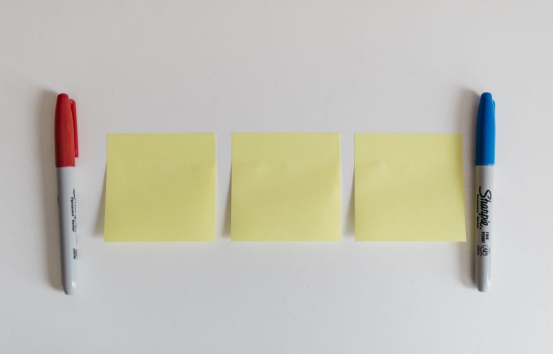 three post-it notes on the wall, with a pen on either side