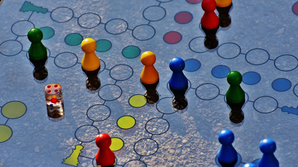 Colourful pieces on a gameboard, with a die alongside