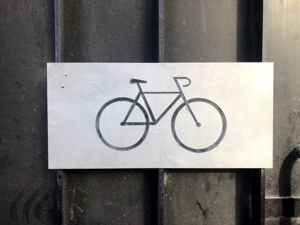 The symbol of a bicycle on a metallic plate on a door.