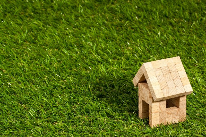 A little wooden house made of blocks set down in the green grass