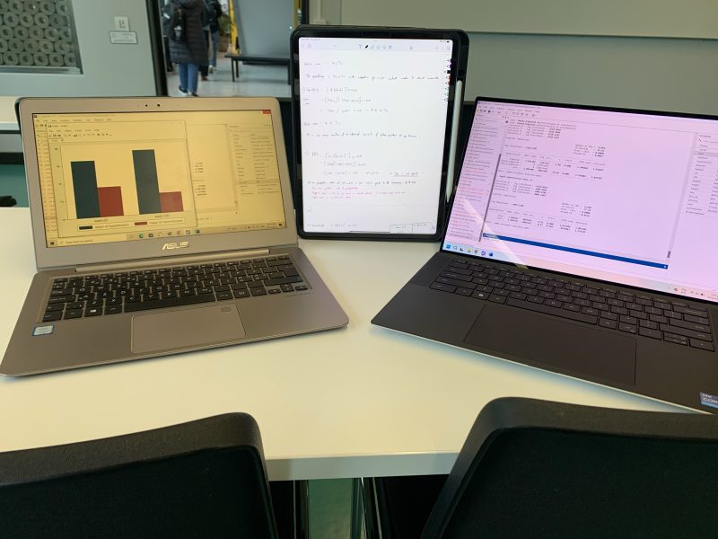 The image shows, two laptops, and an iPad with all of the formulas, codes and descriptions required to complete a Stata exercise.