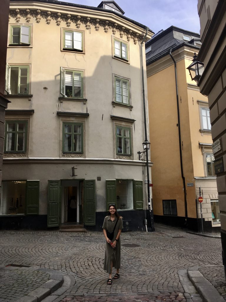 A photo of a girl in a dress in front of an old building.