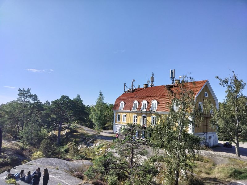 A big yellow house between trees and rocks