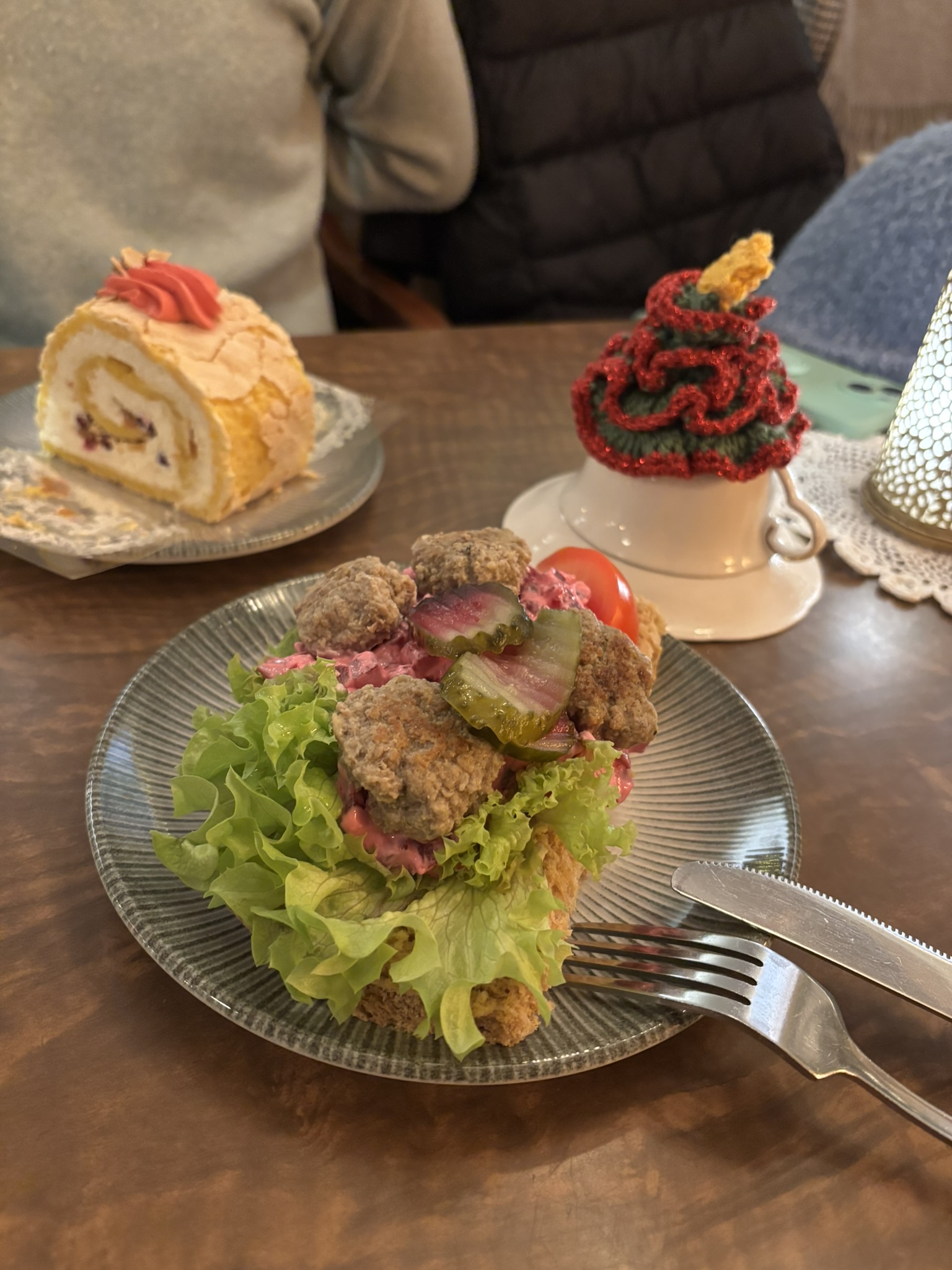 A cold meatball sandwhich with a semla roll cake and some croetched christmas decorations in a cafe