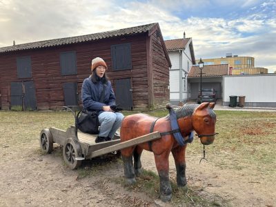 A girl looking shocked on the carriage of a miniature horse statue/display