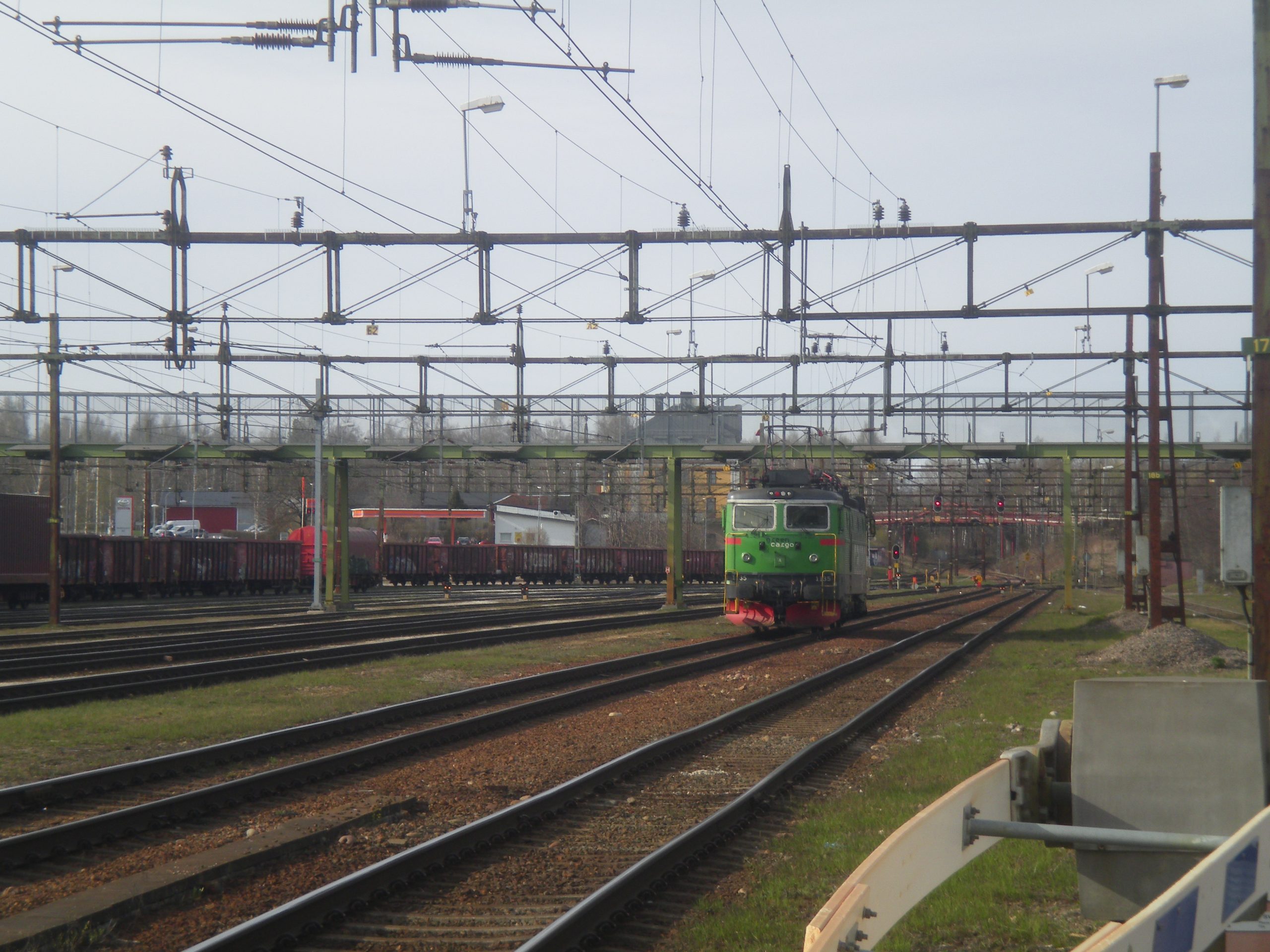 multiple train tracks and there is a small green train segment in the distance with no trailing containers. 
