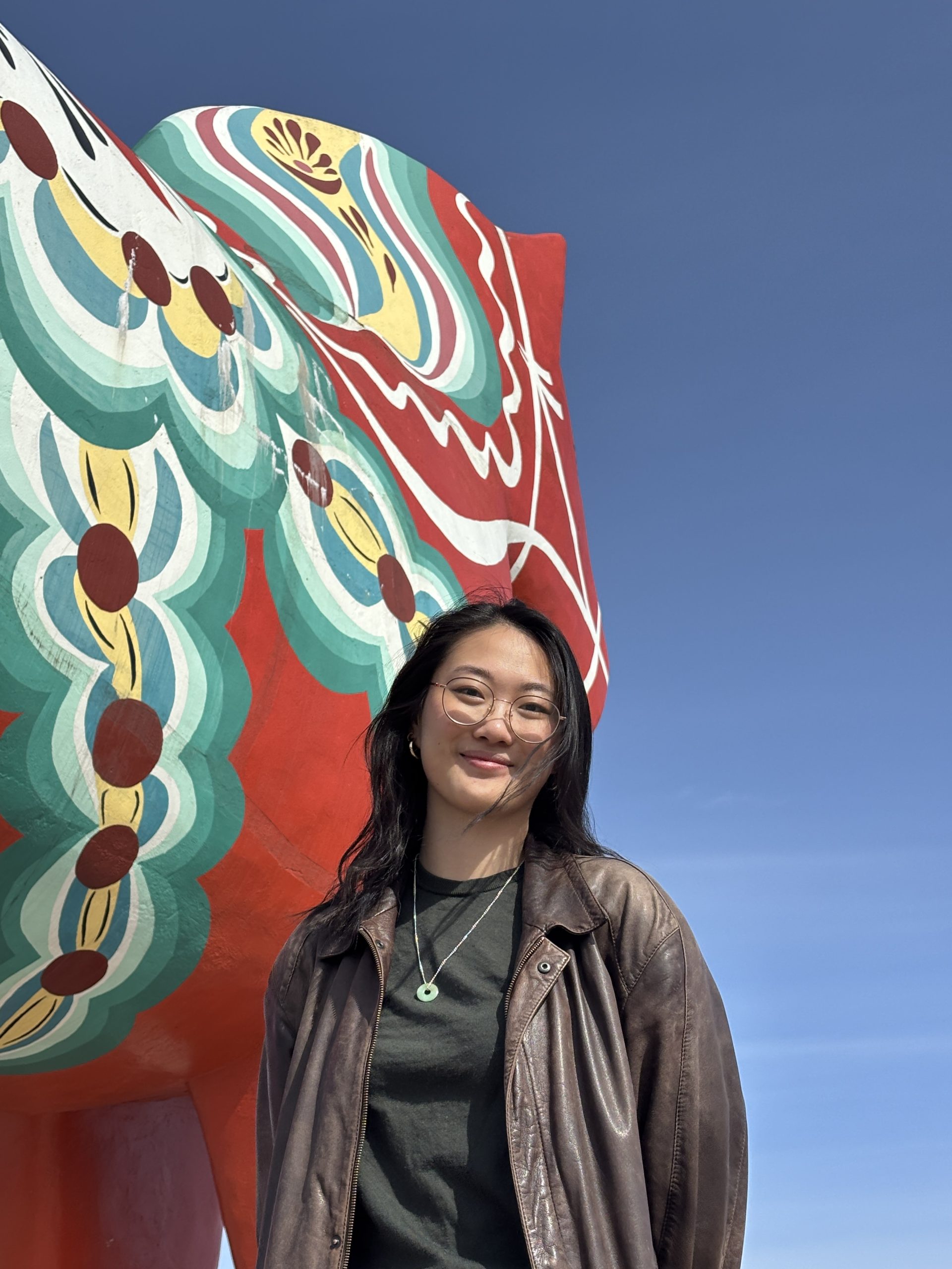 A smiling girl in front of the world's largest dala horse.
