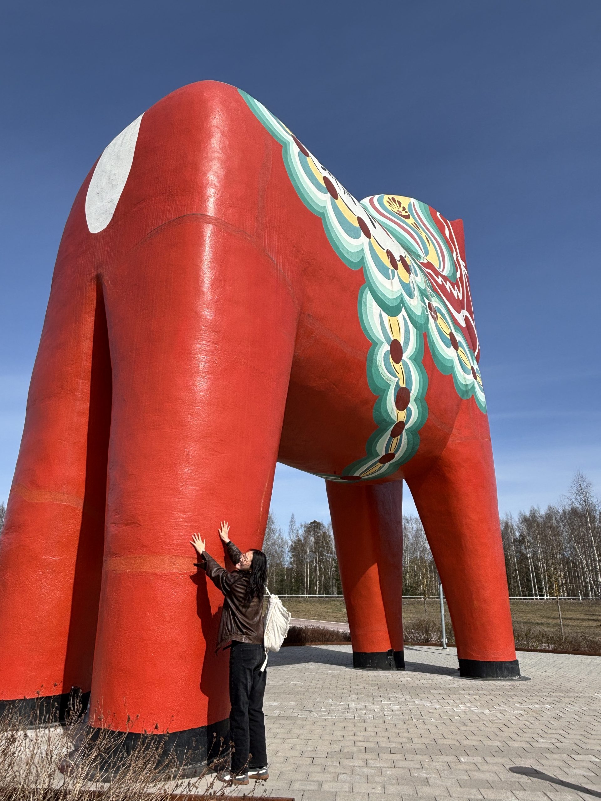 A girls stands at the foot of the world's largest dala horse for size reference. She is less than 1/6th of the tallest part of the horse. 