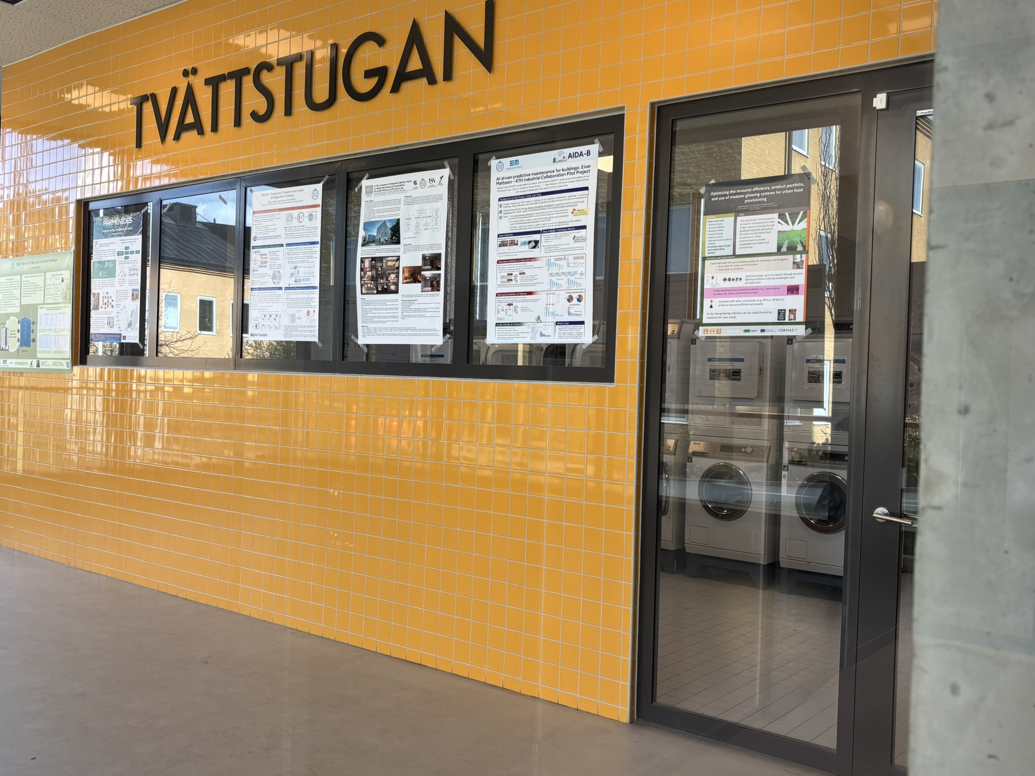 A large orange facade with a glass door in the right edge. Through the door glass, you can see rows of washing machines and drying machines. 