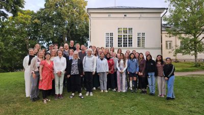 Group of students and professors in front of a yellow house