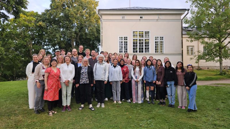 Group of students and professors in front of a yellow house